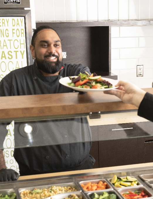 A line cook hands a plate of food over a counter to the customer.