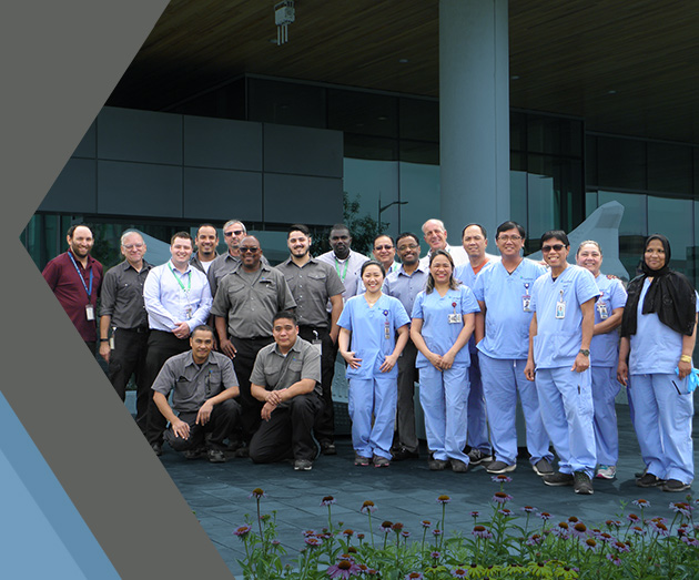 Dexterra emloyees from various industries gather for a group shot, wearing scrubs, custodial outifts and office attire