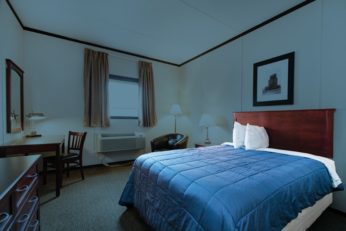 Une chambre d’hôtel avec des draps bleus et des taies d’oreiller blanches contre le mur droit