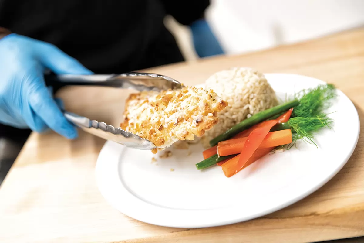 Une personne qui met de la nourriture sur une assiette avec des pinces