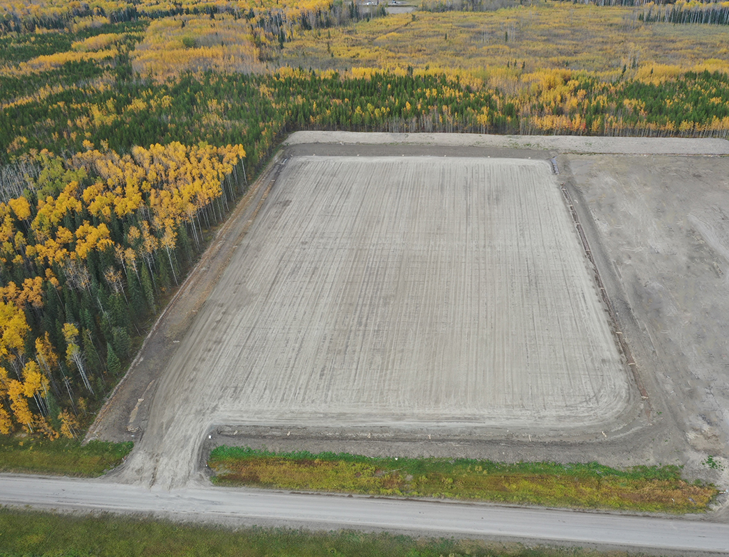 large empty cement lot surrounded by field