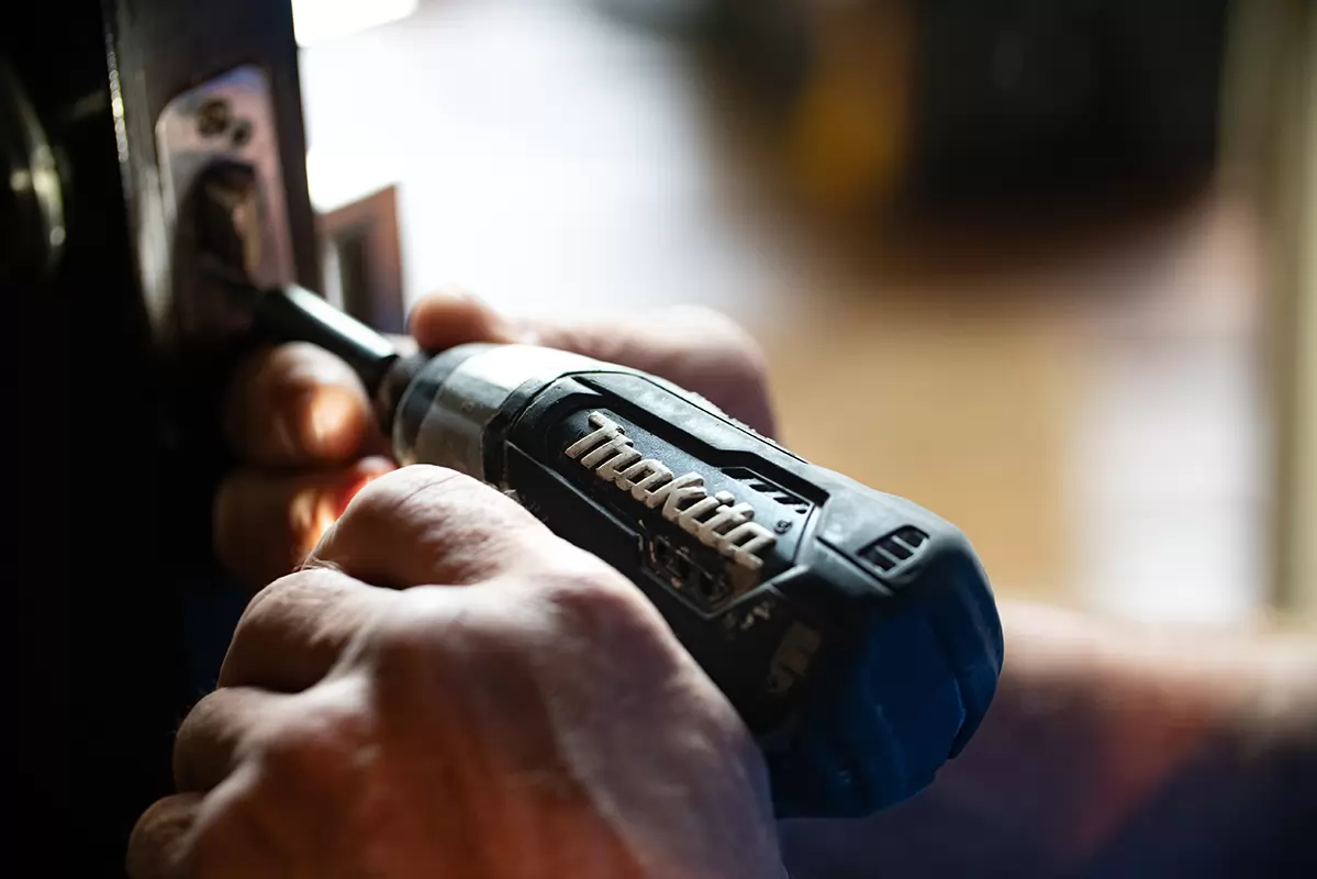 Une perceuse Makita qui visse dans une charnière de porte
