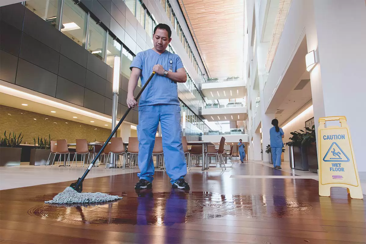 Le personnel d’entretien d’un établissement qui passe la vadrouille sur le plancher d’un grand bâtiment
