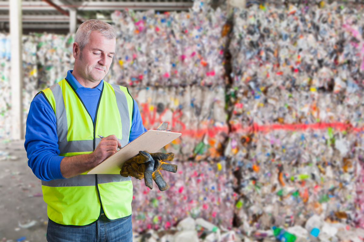 man holding clip board at recycling plant