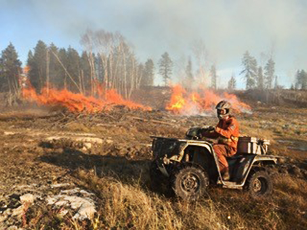 Un homme sur un 4x4 qui conduit à travers un terrain boisé en feu